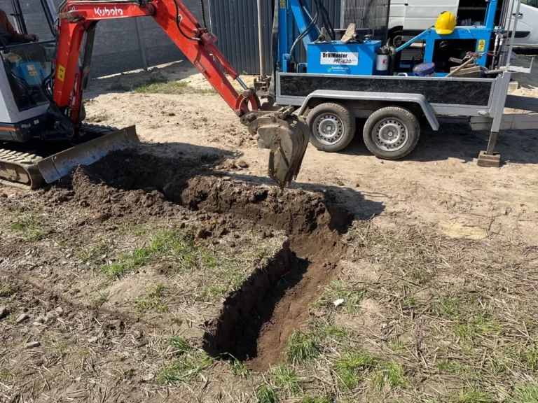 Minikoparka wykonuje wykop pod szambo betonowe na działce – przygotowanie terenu do montażu zbiornika.