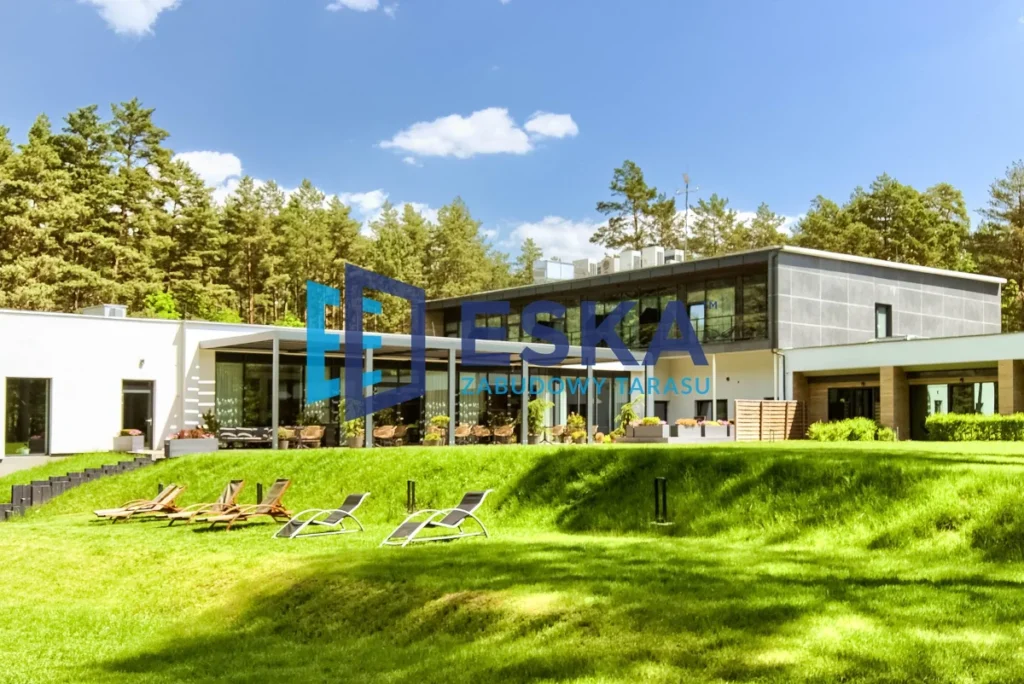 Pergola tarasowa ESKA przy nowoczesnym obiekcie z dużym ogrodem i leżakami na trawie