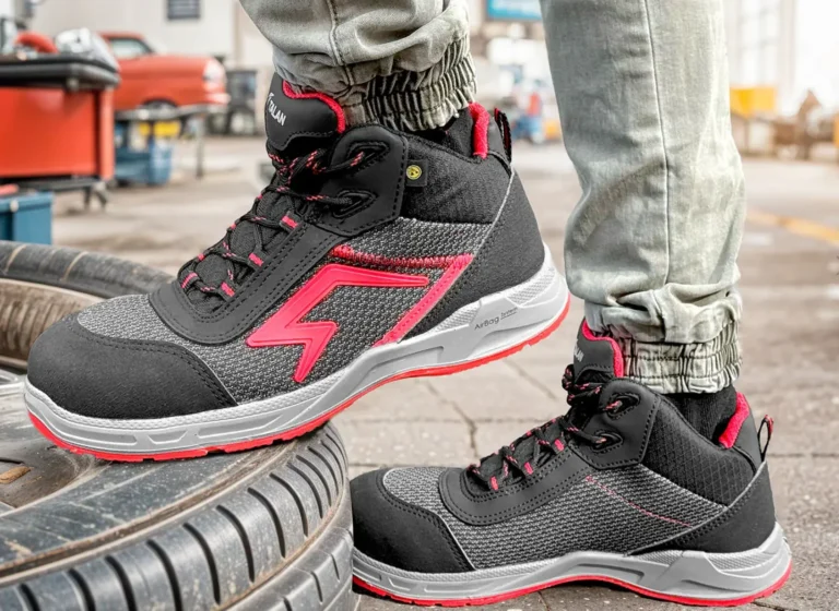 Czarno-czerwone buty robocze za kostkę z grubą podeszwą na industrialnym tle