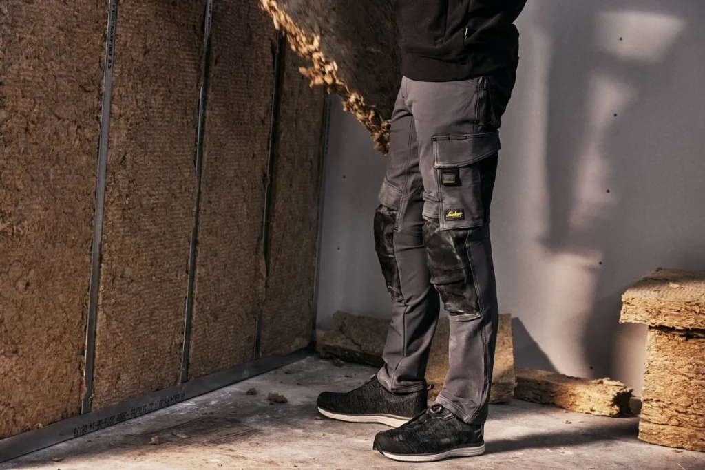 Szare spodnie robocze z wzmocnieniami na kolanach podczas pracy we wnętrzu budowlanym