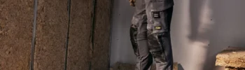 Szare spodnie robocze z wzmocnieniami na kolanach podczas pracy we wnętrzu budowlanym