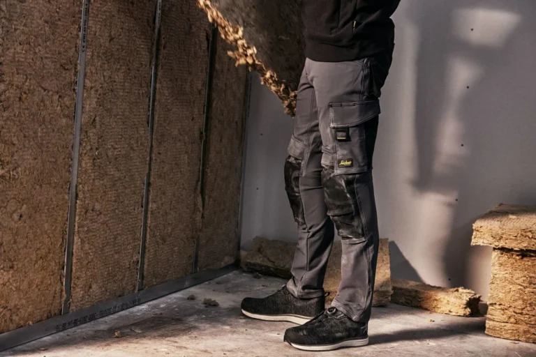 Szare spodnie robocze z wzmocnieniami na kolanach podczas pracy we wnętrzu budowlanym