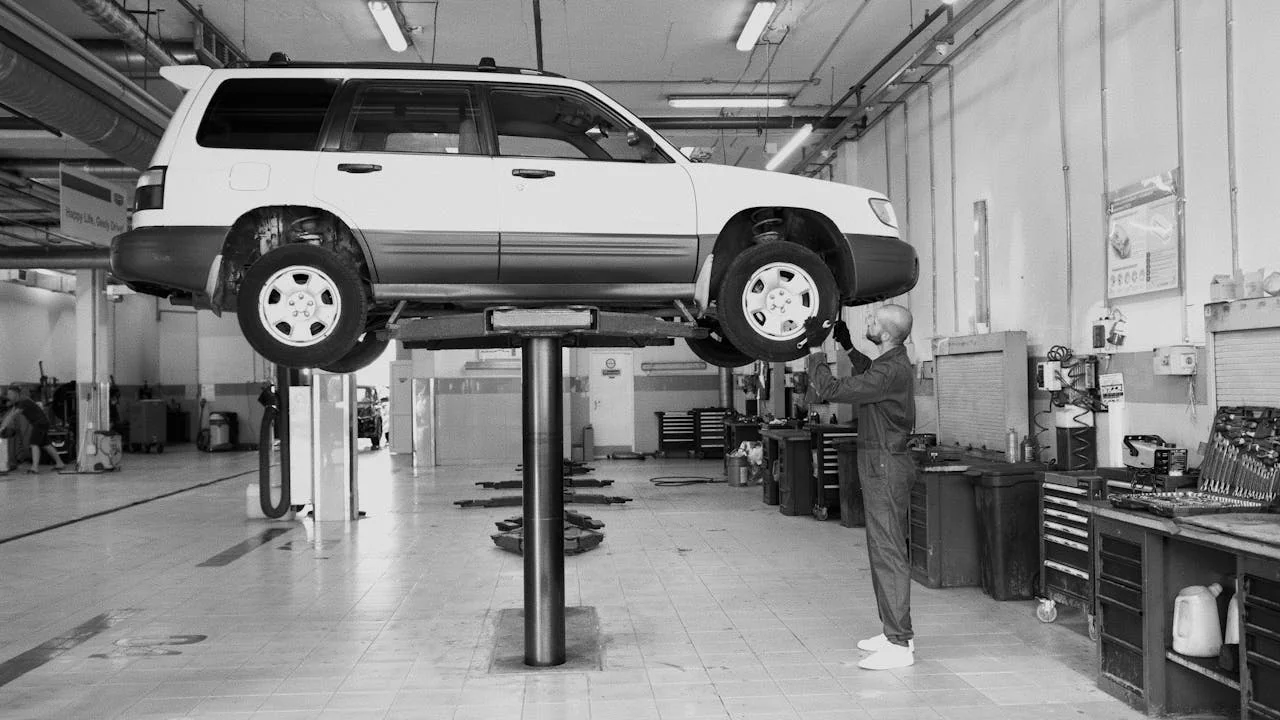 Samochód na podnośniku w warsztacie podczas kontroli podwozia przez mechanika