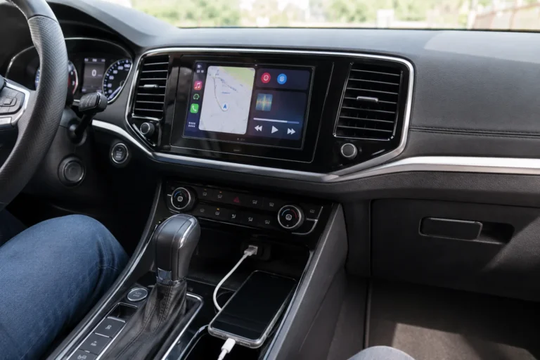 Ekran multimedialny w samochodzie z uruchomionym Android Auto i Apple CarPlay oraz telefonem podłączonym kablem USB