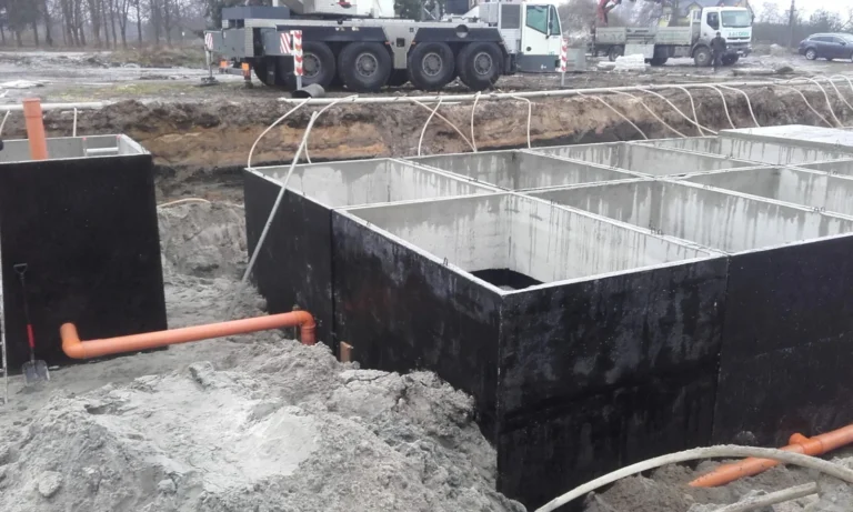 Montaż półpodziemnego zbiornika przeciwpożarowego z prefabrykowanych elementów betonowych na terenie inwestycji przemysłowej.